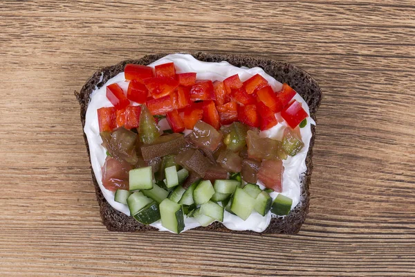 Sanduíche de legumes coloridos, de perto. Pimentos frescos, tomates, pepino, cebola e queijo em pão preto. Vista superior — Fotografia de Stock