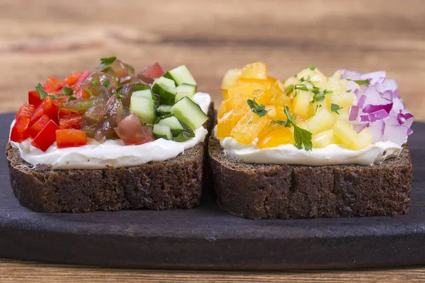 Sándwich de verduras de colores, de cerca. Pimientos frescos, tomates, pepino, cebolla y queso sobre pan negro. Vista superior —  Fotos de Stock