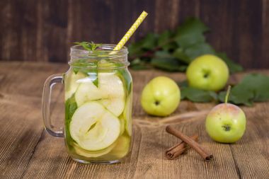 Elma dilim ve ahşap bir masa üzerinde temiz su ve taze elma nane yaprakları ile diyet Detoks içecek
