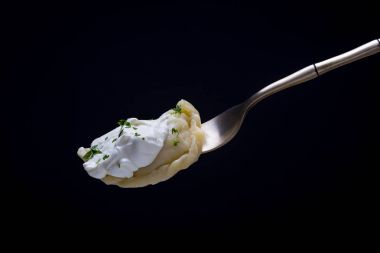 Ukrayna ve Rus yemekleri - vareniki veya köfte patates püresi veya süzme peynir, ekşi krema ve maydanoz üzerinde siyah bir zemin üzerine çatal