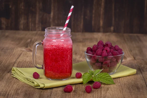 Raspberries juice smoothie shake in glass mug and raw raspberry on wooden background, close up