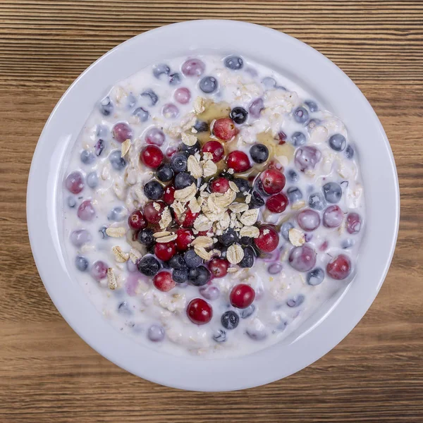 Müsli gjord av blåbär, tranbär, havregryn med yoghurt och honung, närbild — Stockfoto