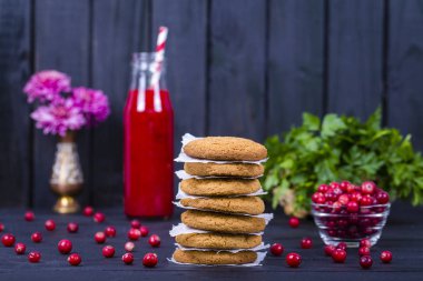 Yulaf kurabiye, kızılcık suyu ve siyah ahşap arka plan üzerinde ham kızılcık yakın çekim