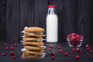 Yulaf kurabiye, süt ve çiğ kızılcık siyah ahşap arka plan, yakın çekim