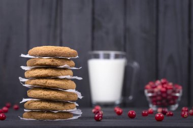 Yulaf kurabiye, süt ve çiğ kızılcık siyah ahşap arka plan, yakın çekim
