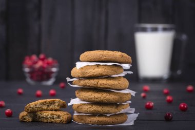 Yulaf kurabiye, süt ve çiğ kızılcık siyah ahşap arka plan, yakın çekim