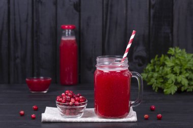 Bir cam kupa ve siyah ahşap arka plan üzerinde ham kızılcık kızılcık suyu kapat