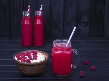 Ahududu suyu bir bardak kupa ve ham ahududu, yoğurt ve siyah ahşap arka plan, ballı yulaf gevreği yapılan müsli yakın çekim