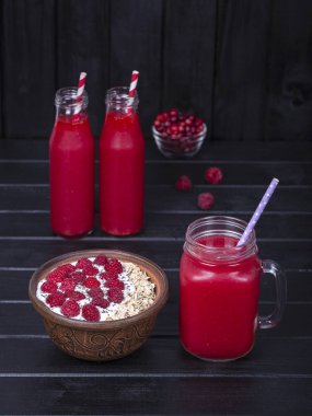 Ahududu suyu bir bardak kupa ve ham ahududu, yulaf gevreği, chia tohum yoğurt ve ballı siyah ahşap arka plan üzerinde yapımı müsli yakın çekim