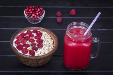 Ahududu suyu bir bardak kupa ve ham ahududu, yulaf gevreği, chia tohum yoğurt ve ballı siyah ahşap arka plan üzerinde yapımı müsli yakın çekim