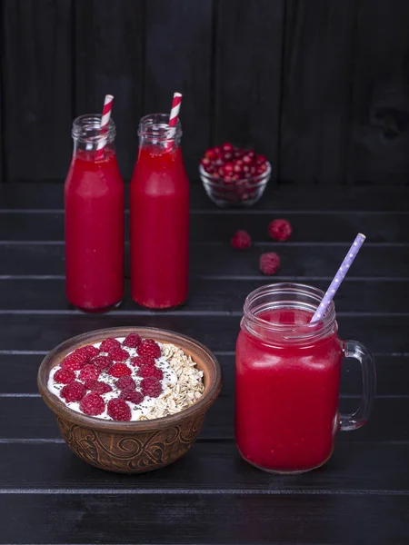 Raspberries juice in a glass mug and muesli made from raw raspberry, oat flakes, chia seeds with yogurt and honey on black wooden background, close up — Stock Photo, Image
