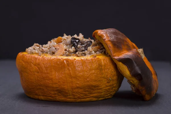 Gustoso autunno zucca ripiena con grano saraceno, carota, cipolla, aglio e prugne sullo sfondo di ardesia nera — Foto Stock