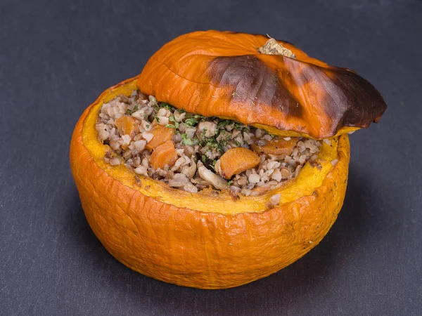 Gustoso autunno zucca ripiena con grano saraceno, carota, cipolla, aglio e prugne sullo sfondo di ardesia nera — Foto Stock