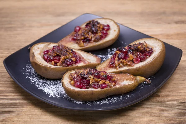 Homemade baked pears with honey, red cranberries and walnuts on wooden background, closeup — Stock Photo, Image