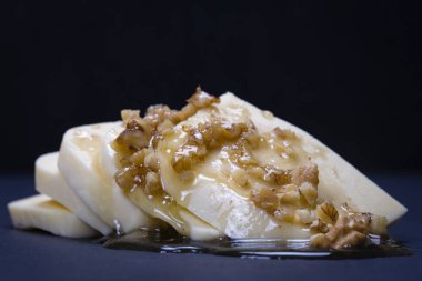Suluguni peynir, ceviz ve siyah arduvaz tabakta bal