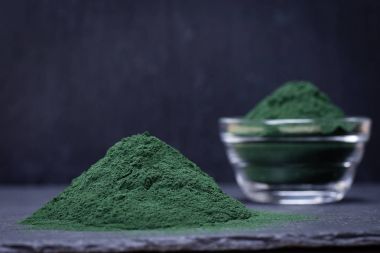 Organik spirulina yosun toz siyah arduvaz plakalı arka plan üzerinde