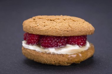 Yulaf kurabiye ham ahududu, bal ve siyah arduvaz arka plan üzerinde yumuşak peynir ile yakın çekim