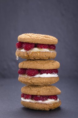 Yulaf kurabiye ham ahududu, bal ve siyah arduvaz arka plan üzerinde yumuşak peynir ile yakın çekim