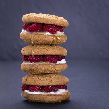 Yulaf kurabiye ham ahududu, bal ve siyah arduvaz arka plan üzerinde yumuşak peynir ile yakın çekim