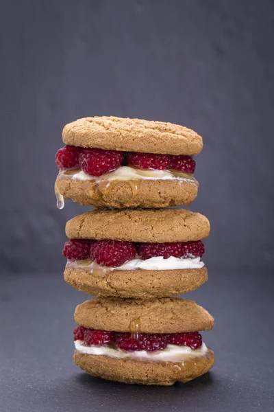 Yulaf kurabiye ham ahududu, bal ve siyah arduvaz arka plan üzerinde yumuşak peynir ile yakın çekim