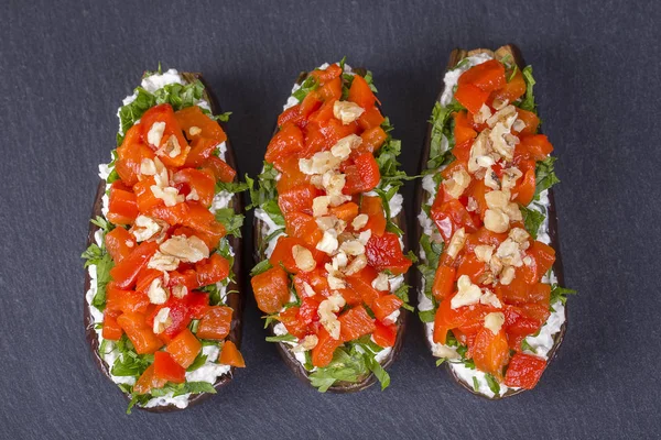 Berenjenas al horno rellenas de verduras, nueces y queso sobre un fondo de pizarra negra, de cerca —  Fotos de Stock