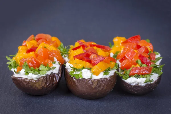 Berenjenas al horno rellenas de verduras y queso sobre un fondo de pizarra negra, de cerca —  Fotos de Stock