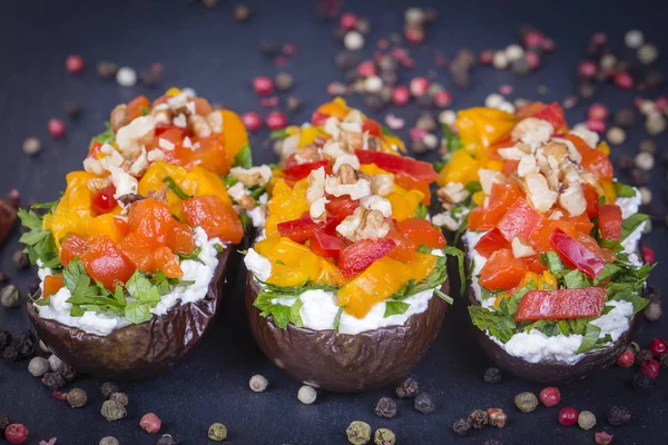 Berenjenas al horno rellenas de verduras, nueces y queso crema sobre un fondo de pizarra negra, de cerca —  Fotos de Stock