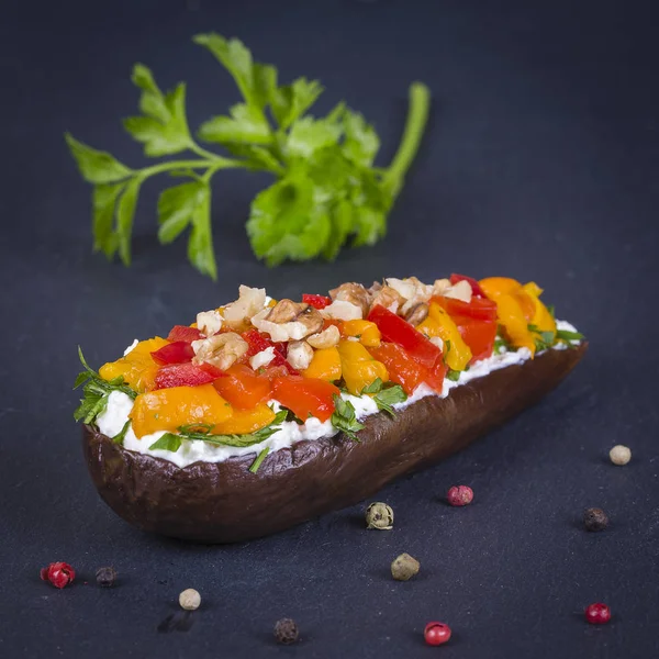 Berenjenas al horno rellenas de verduras, nueces y queso crema sobre un fondo de pizarra negra, de cerca —  Fotos de Stock