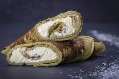 Yeşil spirulina ile ev yapımı gözleme bir siyah arduvaz arka plan üzerinde beyaz peynir kuru üzüm ile doldurulmuş, yakın çekim