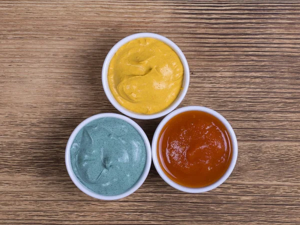 Kırmızı domates sosu, zerdeçal sos ve spirulina sos ahşap arka planda, üstten görünüm