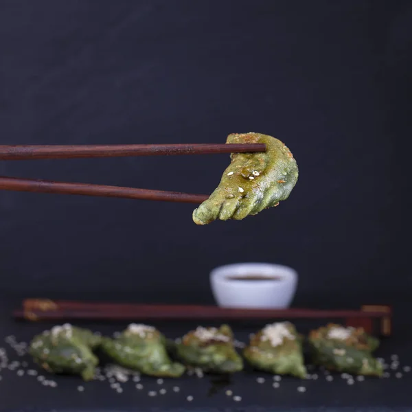 Los platos ucranianos y rusos - vareniki verde o albóndigas con carne de res o puré de papas o requesón en la masa, junto con la espirulina sobre un fondo de pizarra negro — Foto de Stock