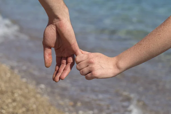 Mãos de casal juntas sobre um fundo natural do mar — Fotografia de Stock