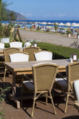 Masa ve sandalyeler plaja yakın boş kafede. Çıralı, Kemer, Türkiye