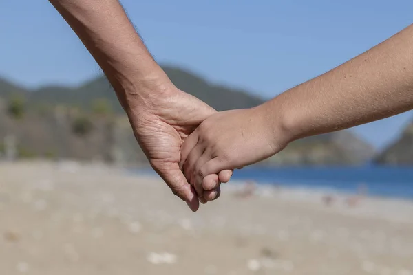 Couple hands held together on a natural sea background — Stock Photo, Image