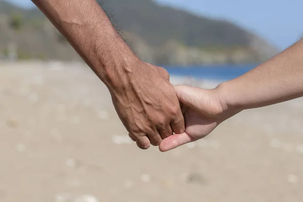 Mãos de casal juntas sobre um fundo natural do mar — Fotografia de Stock