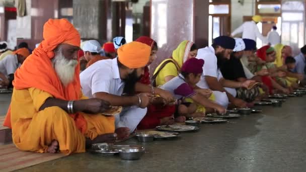 गरीब भारतीय लोग सिख स्वर्ण मंदिर, अमृतसर, भारत में एक सूप रसोई में मुक्त भोजन खा रहे हैं — स्टॉक वीडियो