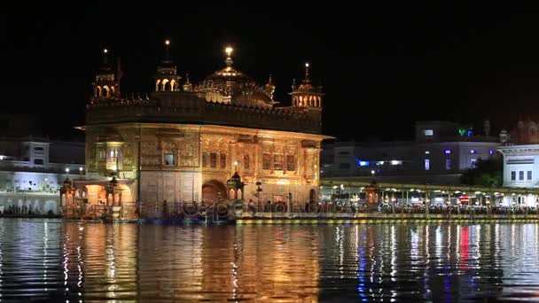 Amritsar, India - 2014. szeptember 28.: Azonosítatlan szikhek és az indiai emberek látogatás a Golden Temple-ban Amritsar, éjjel. Szikh zarándokok utazás az egész imádkozni, ezen a Szent helyen Indiában. — Stock videók