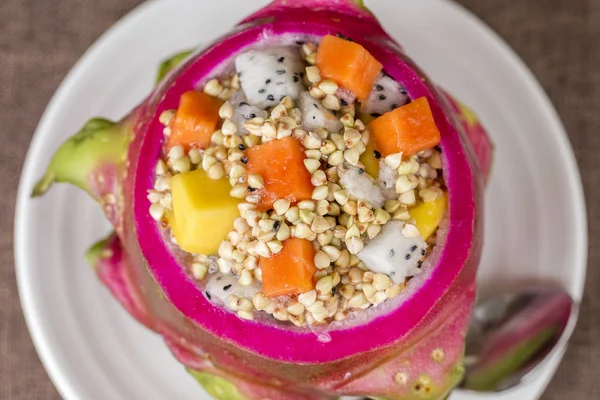 Ensalada de frutas tropicales frescas con trigo sarraceno verde y miel en piel de fruta de dragón, de cerca — Foto de Stock