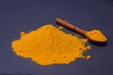 Organik zerdeçal, curcuma toz siyah arduvaz plakalı arka plan üzerinde. Sağlıklı köri tozu