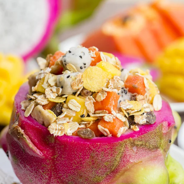 Salat aus frischen tropischen Früchten mit Haferflocken, Rosinen, Nüssen und Honig in Drachenfruchtschale, Nahaufnahme — Stockfoto