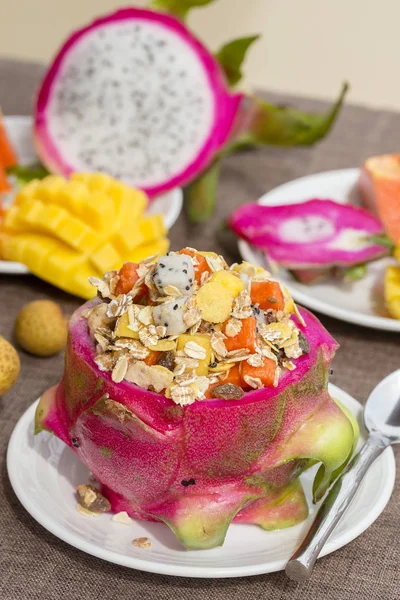 Ensalada de frutas tropicales frescas con copos de avena, pasas, nueces y miel en piel de fruta de dragón, de cerca — Foto de Stock