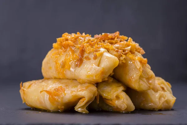 Los platos ucranianos - los rollos caseros rellenos de col con el arroz y la carne en la salsa de tomate sobre el fondo negro de pizarra —  Fotos de Stock