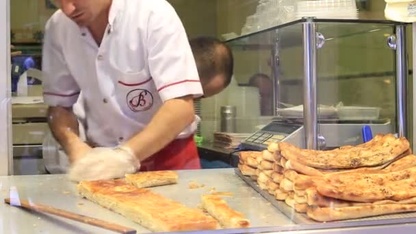 Hombre prepara pasteles tradicionales turcos a los visitantes en un restaurante en la calle istiklal en Estambul, Turquía . — Vídeos de Stock