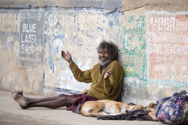 Poor man and dog in Varanasi, India clipart