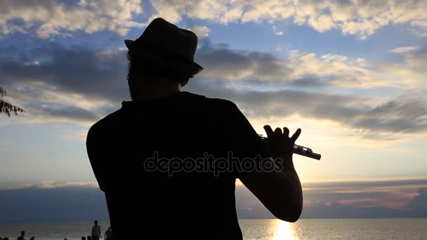 Силуэт играет на флейте на закате на пляже во время вечеринки в честь полнолуния на острове Панган, Таиланд — стоковое видео