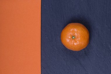 Taze mandarin siyah slates ve turuncu bir peçete yanında yatıyor. Sağlıklı, organik, vegan gıda, vitaminler kavramı. Üstten Görünüm. Taze portakal, mandalina arka plan