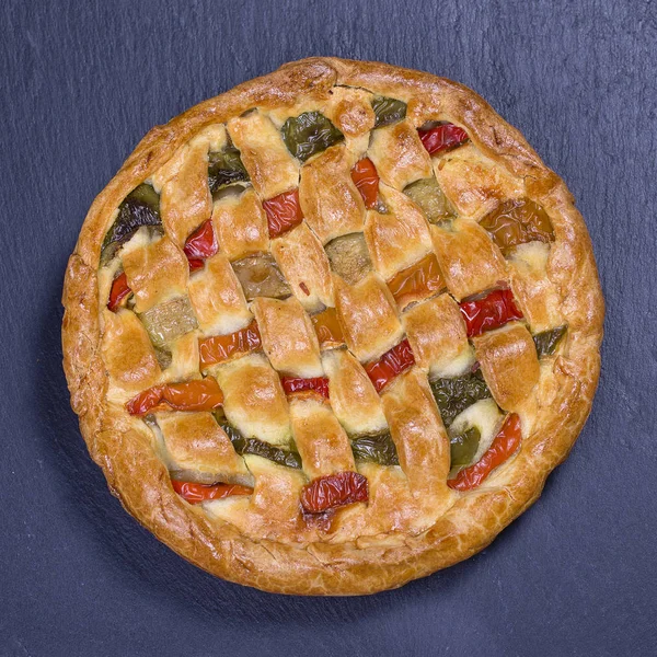 Homemade organic chicken pie with vegetables to eat on black slate background
