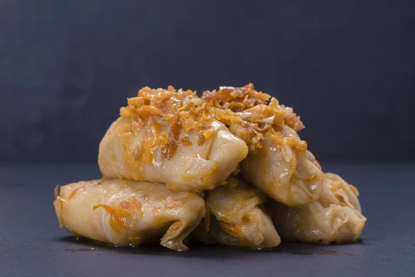 Los platos ucranianos - los rollos caseros rellenos de col con el arroz y la carne en la salsa de tomate sobre el fondo negro de pizarra — Foto de Stock