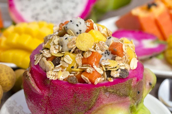 Ensalada de frutas tropicales frescas con copos de avena, pasas, nueces y miel en piel de fruta de dragón, de cerca — Foto de Stock