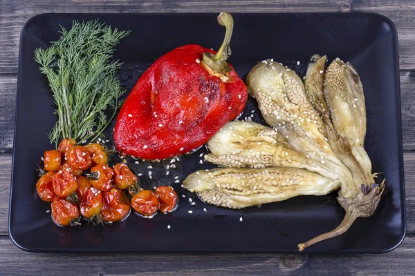 Verduras asadas berenjena y pimiento rojo con salsa de tomate en plato negro —  Fotos de Stock